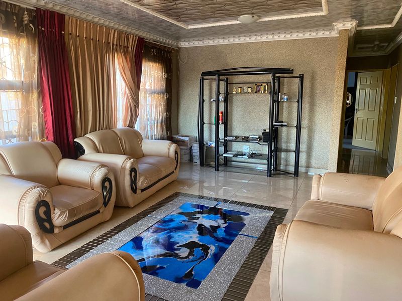 A living room featuring tiled flooring, textured wall finishes, and decorative ceiling molding, offering a dated but functional space for relaxation.