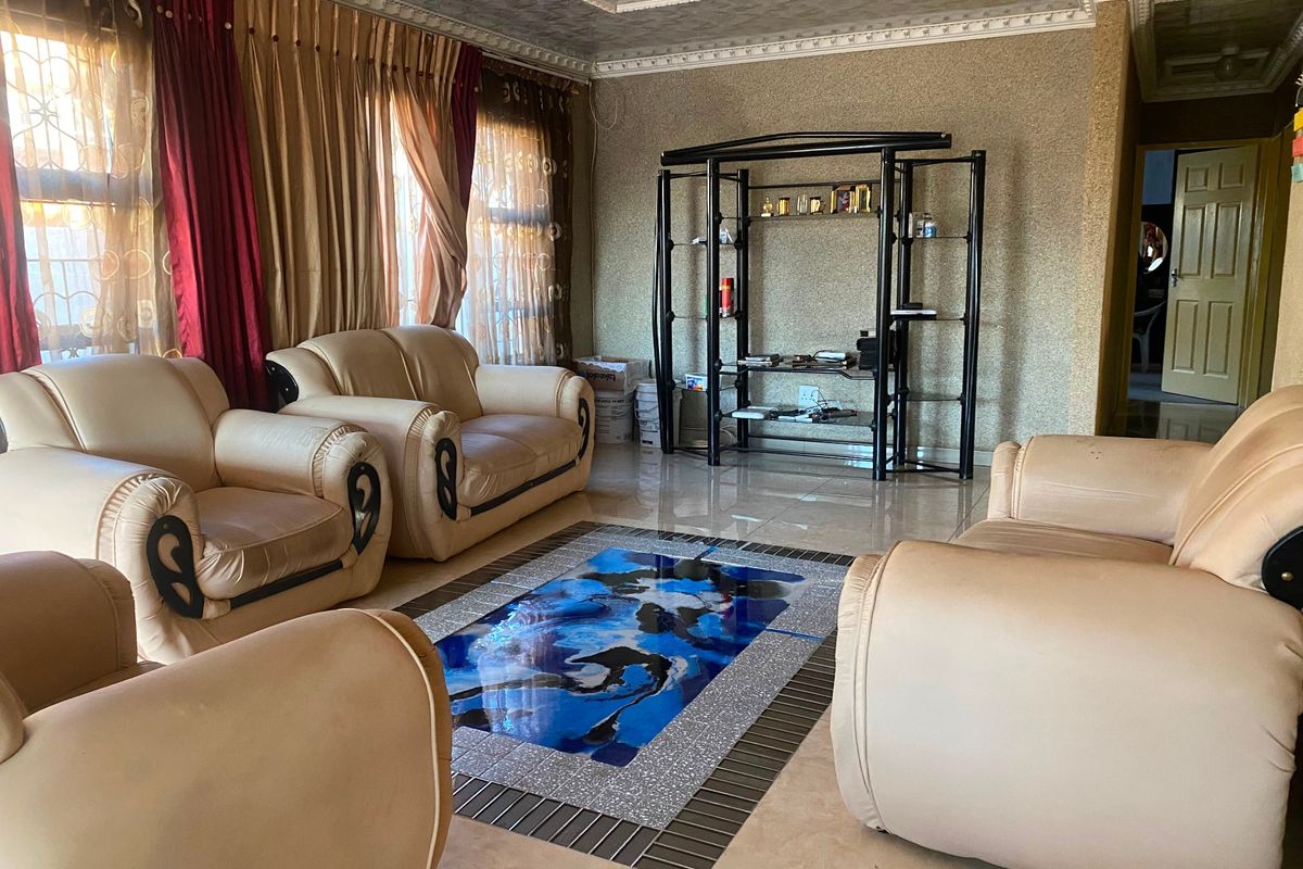 A living room featuring textured wallpaper, decorative ceiling molding, and tiled flooring with a central decorative inlay.