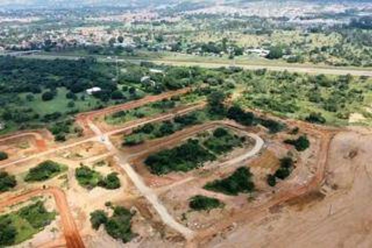An aerial view of an undeveloped residential estate site showing cleared land plots and unpaved road infrastructure.