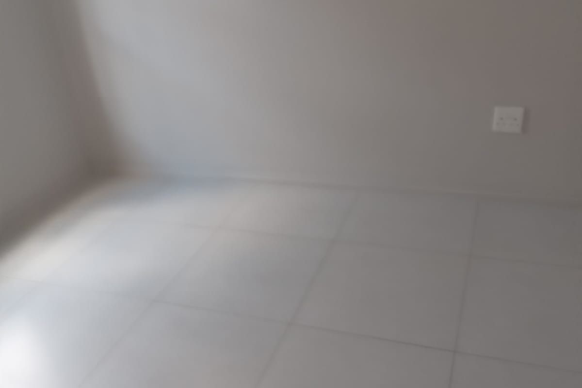 An empty bedroom featuring neutral tiled flooring and a clean wall finish, providing a blank canvas for interior design.