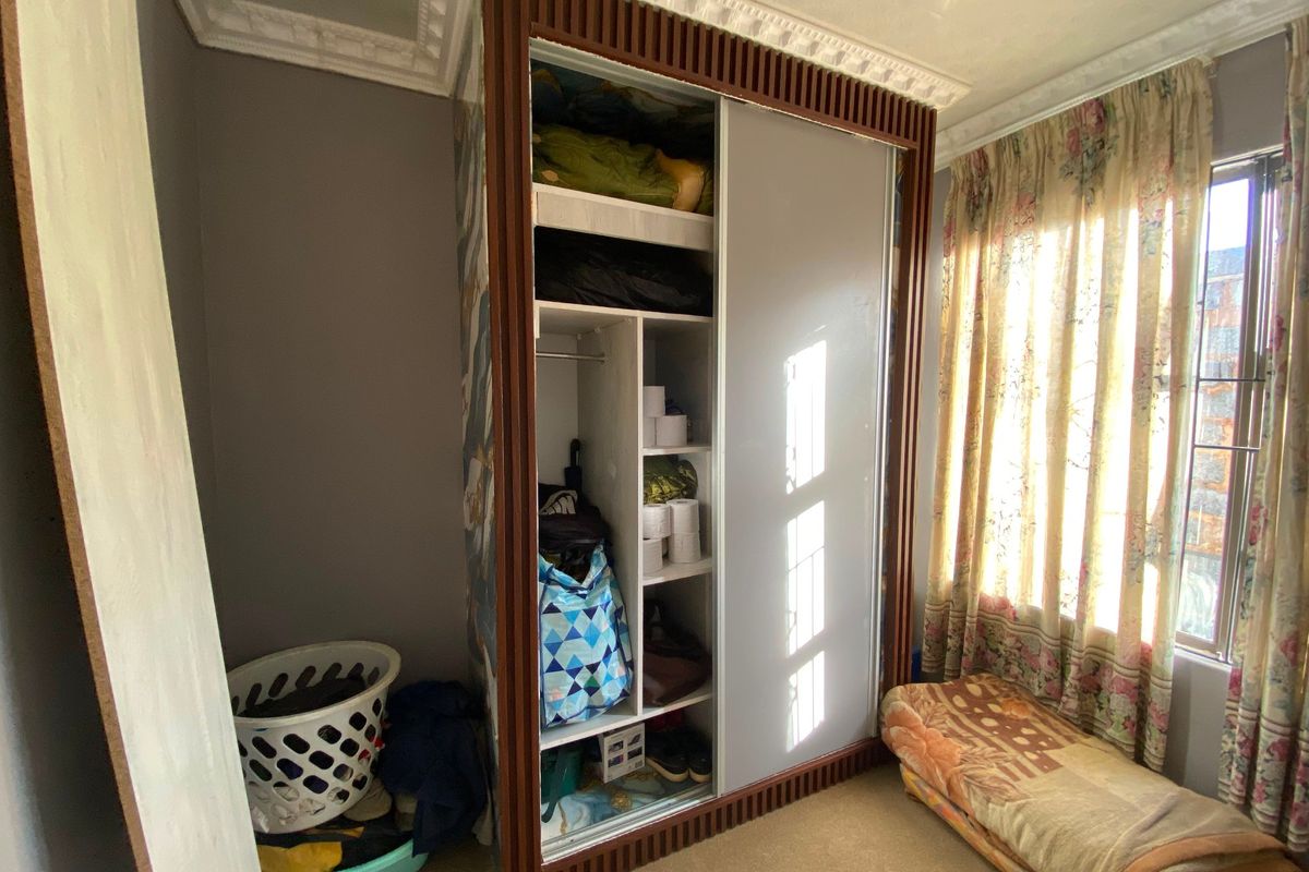 A bedroom featuring a large built-in wardrobe with sliding doors and decorative ceiling cornicing.
