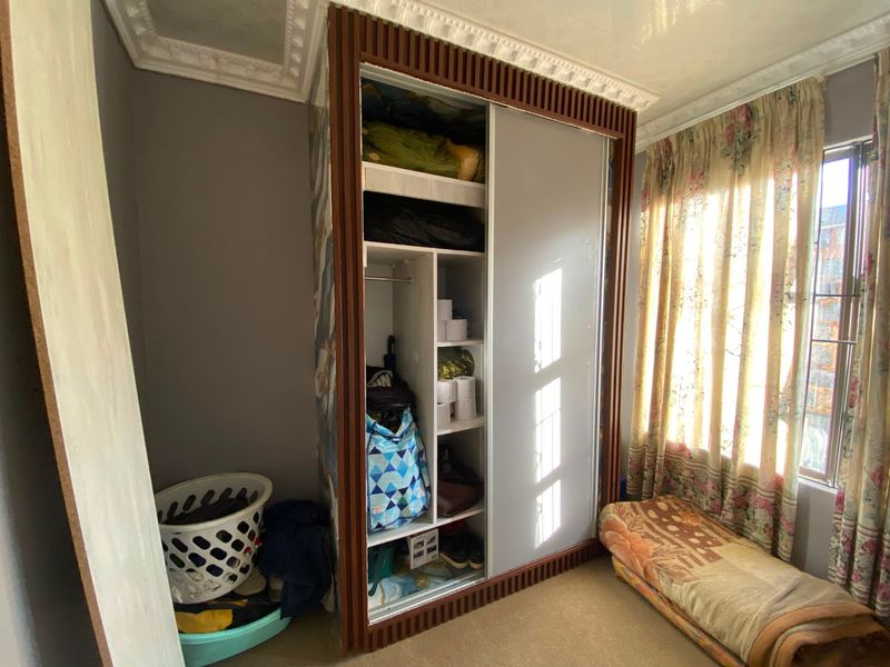 A bedroom featuring a large built-in wardrobe with sliding doors and decorative ceiling cornicing.