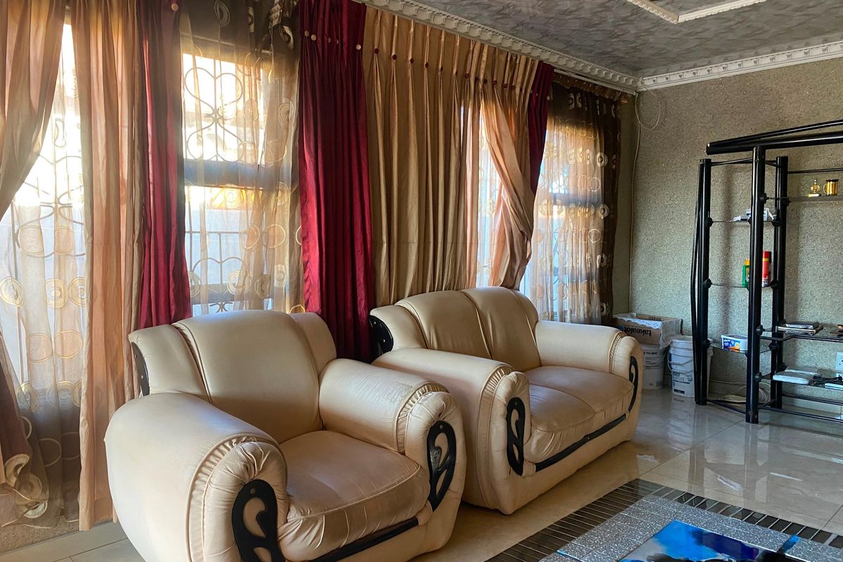 A living room featuring tiled flooring, textured wall finishes, and decorative ceiling molding, providing a dated but functional living space.
