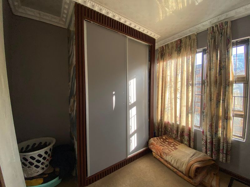 Bedroom featuring a large built-in wardrobe with decorative wood trim, carpeted flooring, and a window with security bars.