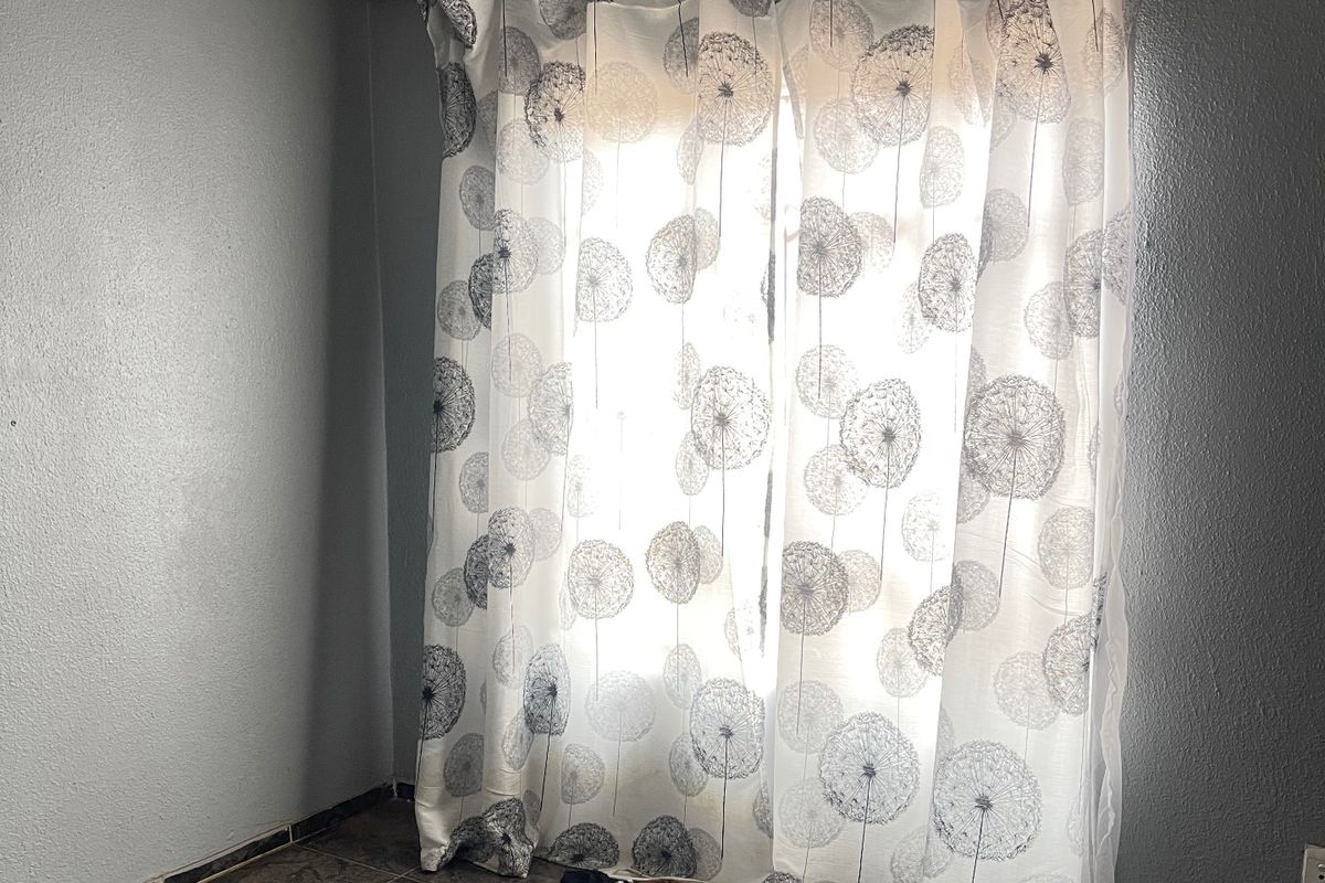 An empty bedroom featuring tiled flooring, a curtain rail, and a simple ceiling light fixture, ready for renovation or staging.