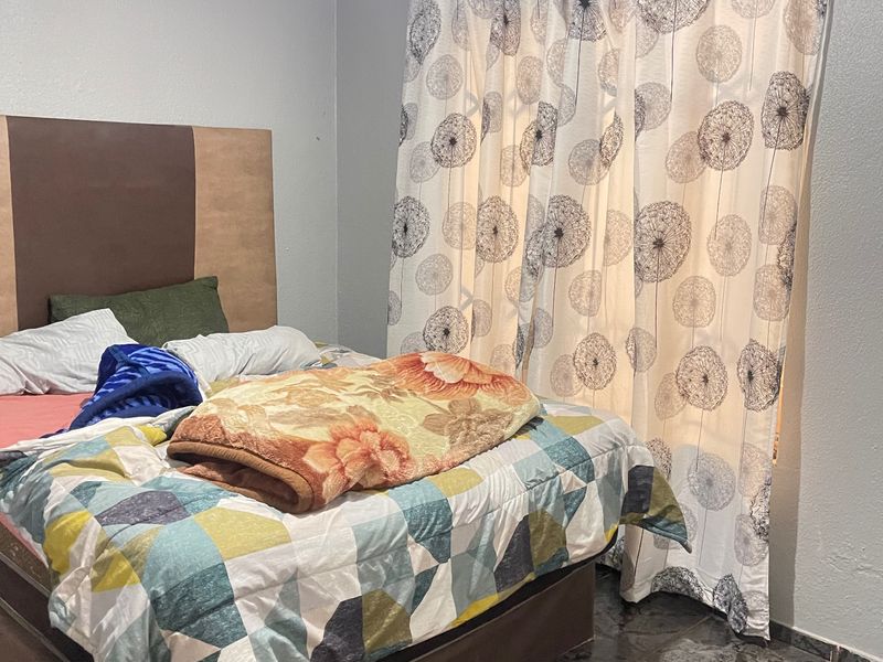 A bedroom featuring tiled flooring and a curtain rod, providing a functional space for rest.