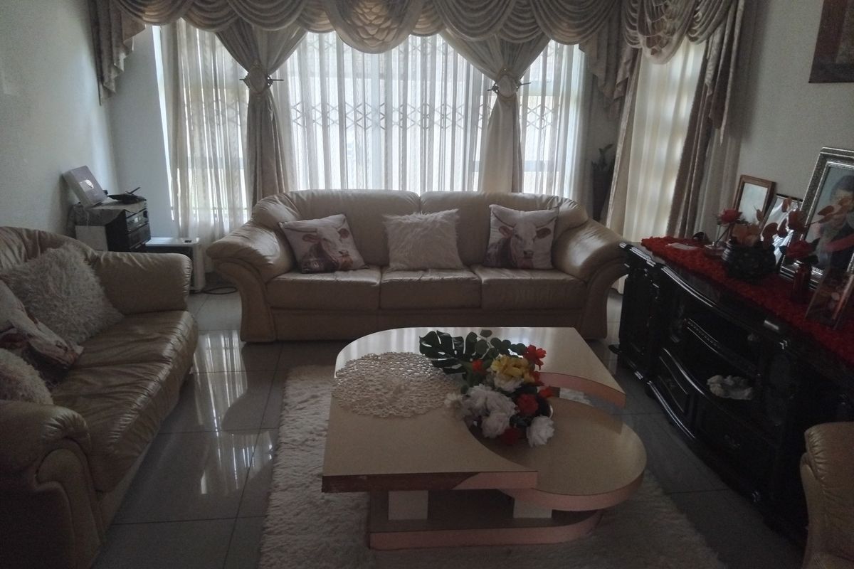 A living room featuring tiled flooring and large windows with security gates, providing a functional space for relaxation.