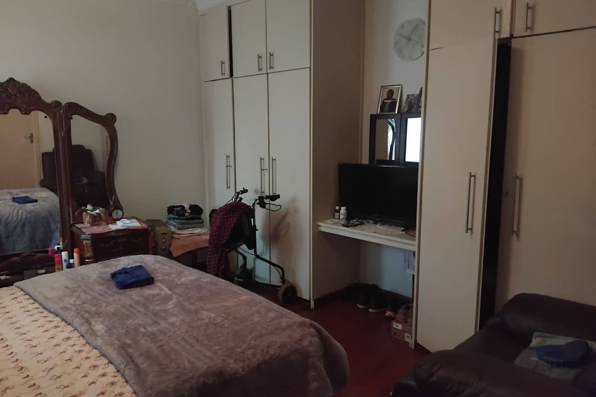 A bedroom featuring extensive built-in cupboard storage, laminate flooring, and decorative ceiling cornicing.