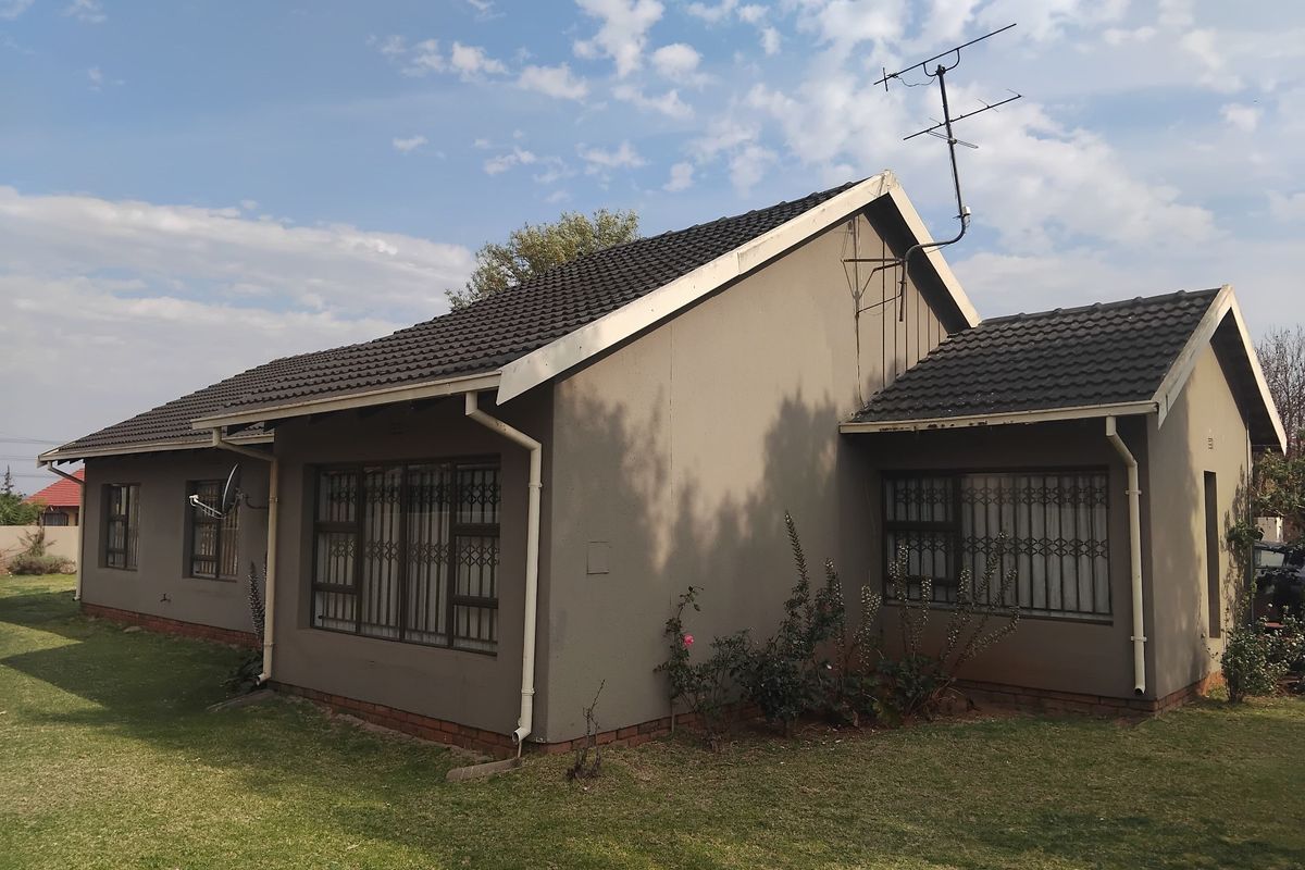 Rear view of a single-story residential house featuring a tiled roof, guttering, and metal security bars on the windows.