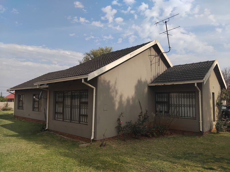 Rear view of a single-story residential house featuring a tiled roof, guttering, and metal security bars on the windows.
