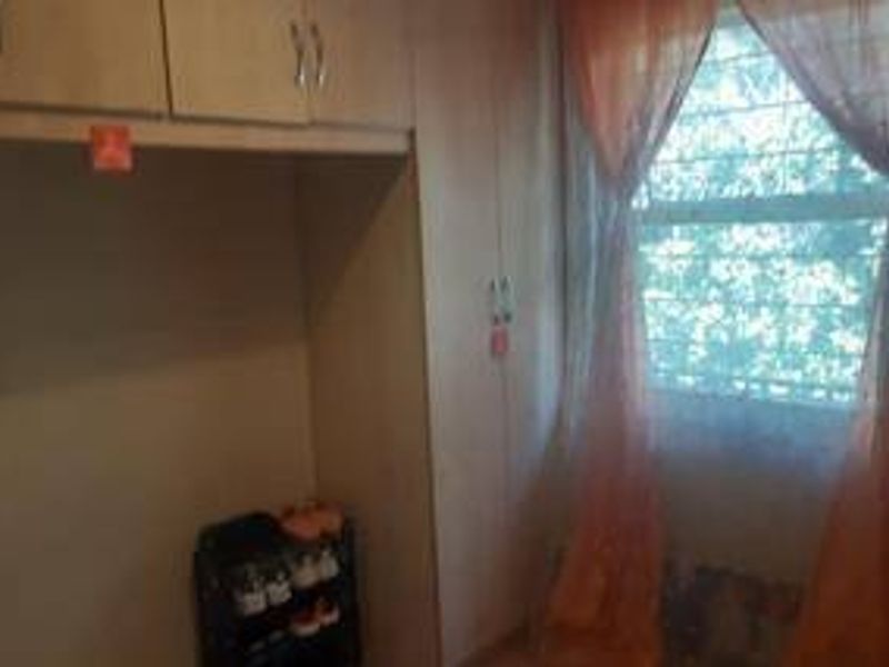 A bedroom featuring built-in cupboards and a window fitted with security bars.