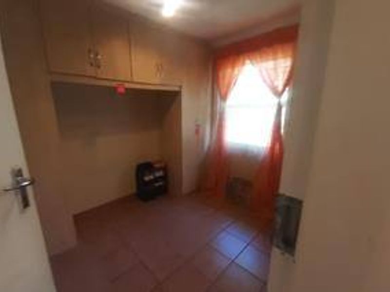 A compact bedroom featuring built-in cupboards and tiled flooring, offering a functional space ready for personalization.