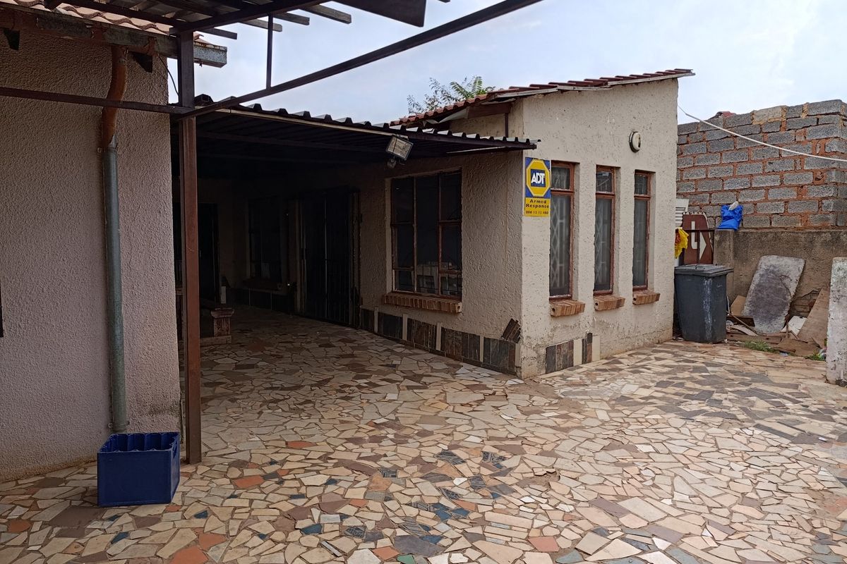 Rear exterior area featuring a covered patio with crazy paving flooring and weathered exterior walls.