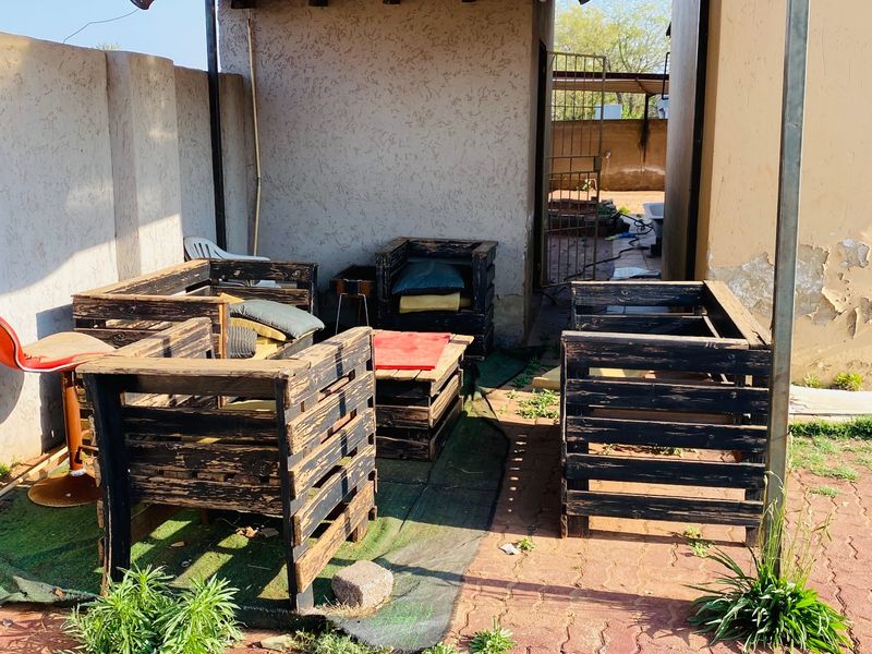 Outdoor patio area featuring a corrugated metal roof structure, paved flooring, and perimeter walling, currently requiring maintenance and cosmetic updates.