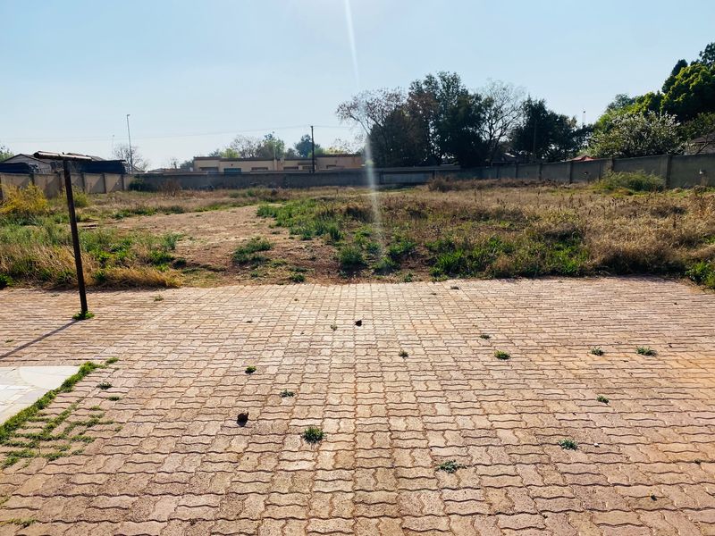 A large, undeveloped backyard area featuring paved sections and a perimeter wall, offering significant potential for landscaping or future expansion.