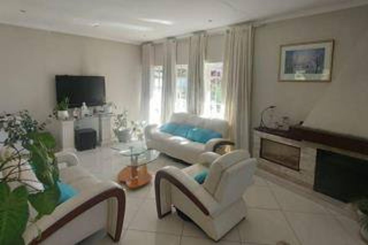 A bright living room featuring tiled flooring, a built-in fireplace, and large windows with curtains, offering a comfortable and functional living space.