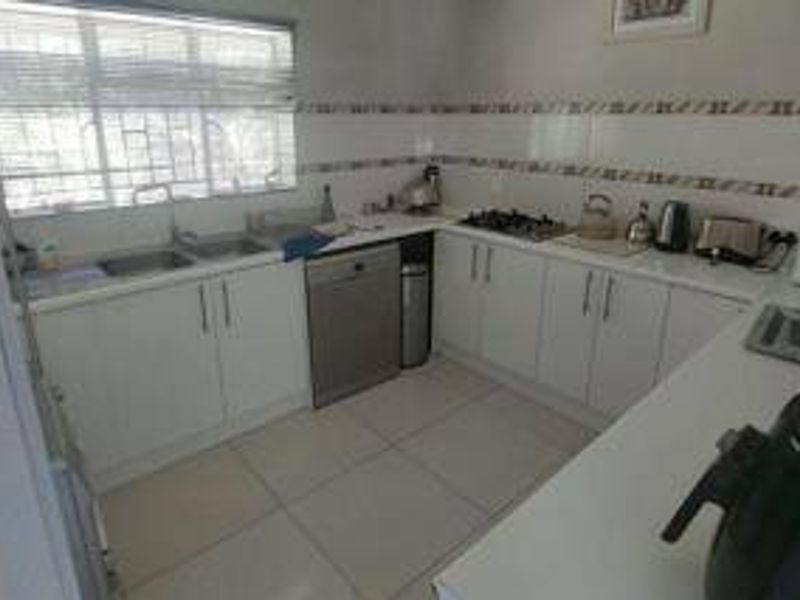 A functional kitchen featuring white cabinetry, tiled splashbacks, gas hob, and tiled flooring, offering a clean and practical workspace.