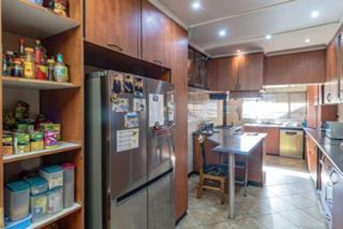 A functional kitchen featuring wood-finish cabinetry, tiled flooring, a breakfast bar, and ample storage space, offering a practical layout for daily meal preparation.