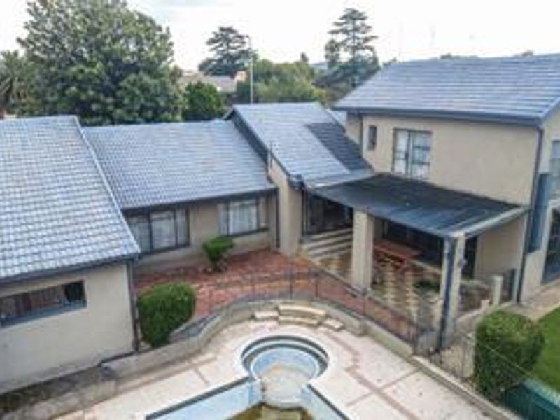 Aerial view of the rear exterior featuring a swimming pool, paved courtyard area, and a covered patio attached to the main house structure.