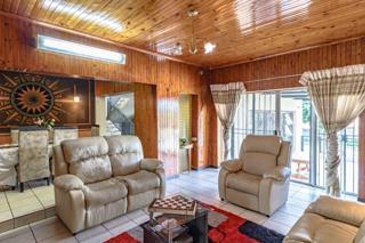 Spacious living area featuring extensive timber-clad walls and ceilings, tiled flooring, and large sliding glass doors providing access to the outdoor area.