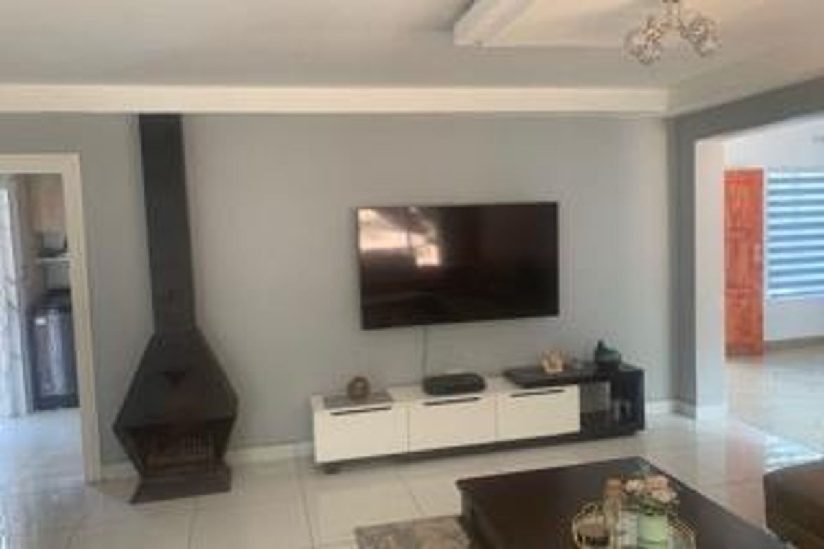 A well-maintained living room featuring tiled flooring, a modern freestanding fireplace, and coved ceiling details, offering a clean and functional living space.
