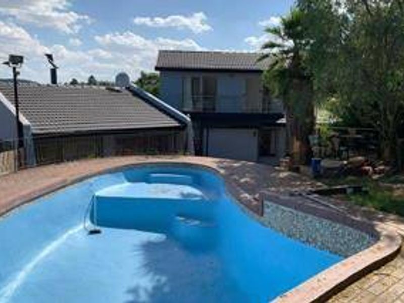 Outdoor pool area featuring a swimming pool with tiled surround, set against the rear elevation of a multi-story residential property.