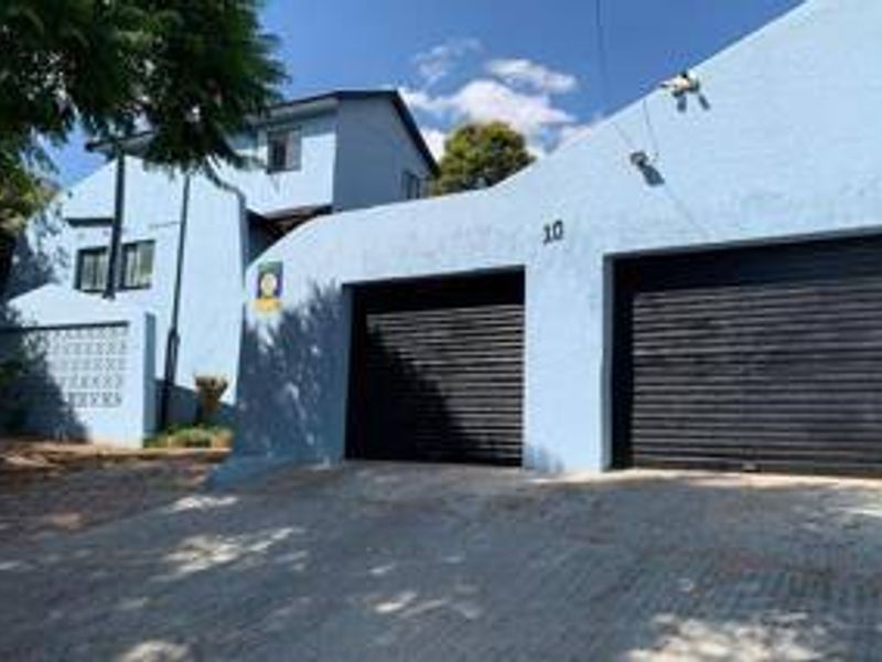 Front elevation of a two-story house featuring a double garage with black roller shutter doors and a paved driveway.