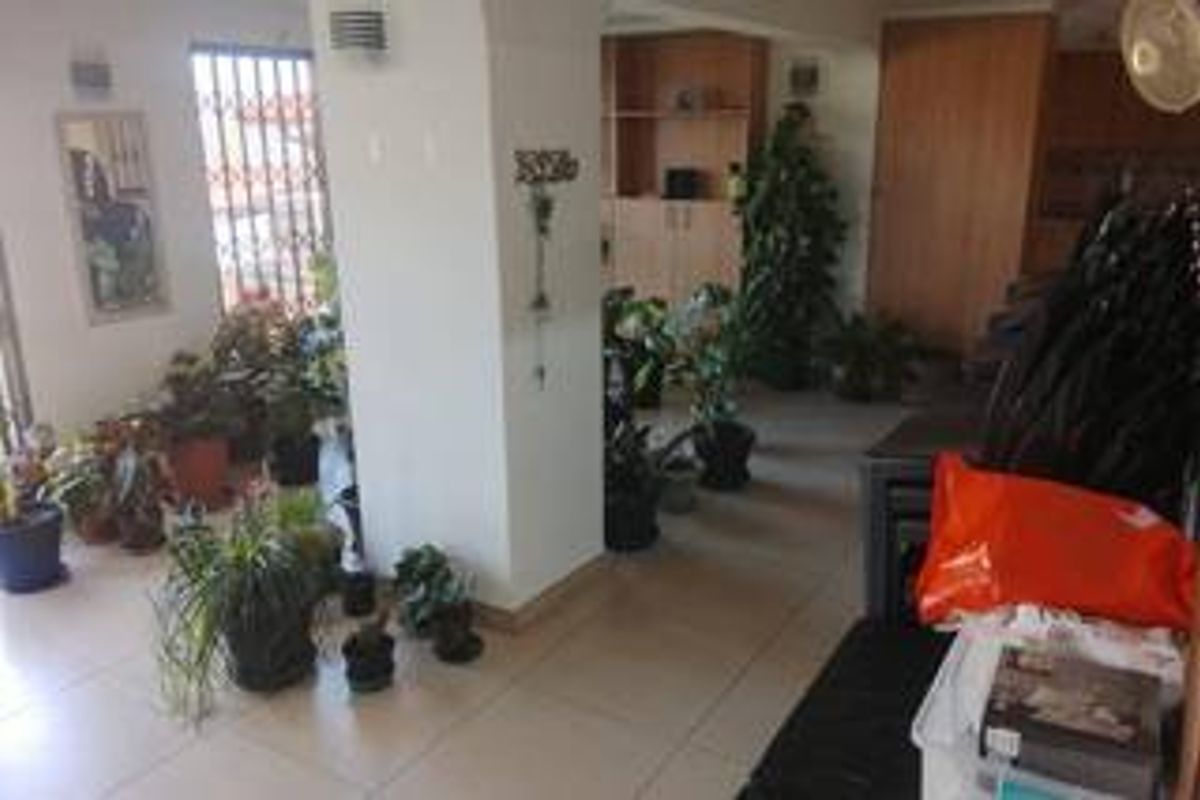 A living area featuring tiled flooring and built-in cabinetry, currently utilized as a plant display space.
