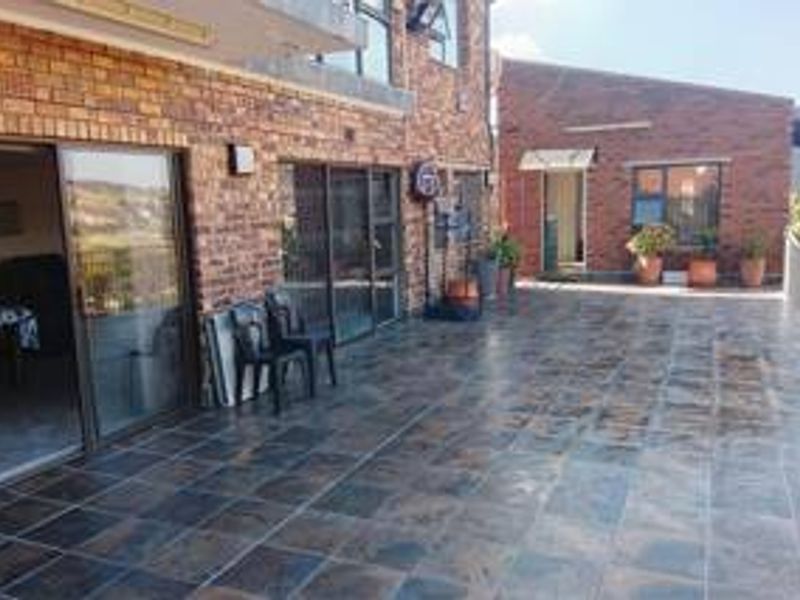 A spacious outdoor patio area featuring tiled flooring, brick exterior walls, and large sliding glass doors providing access to the interior living space.