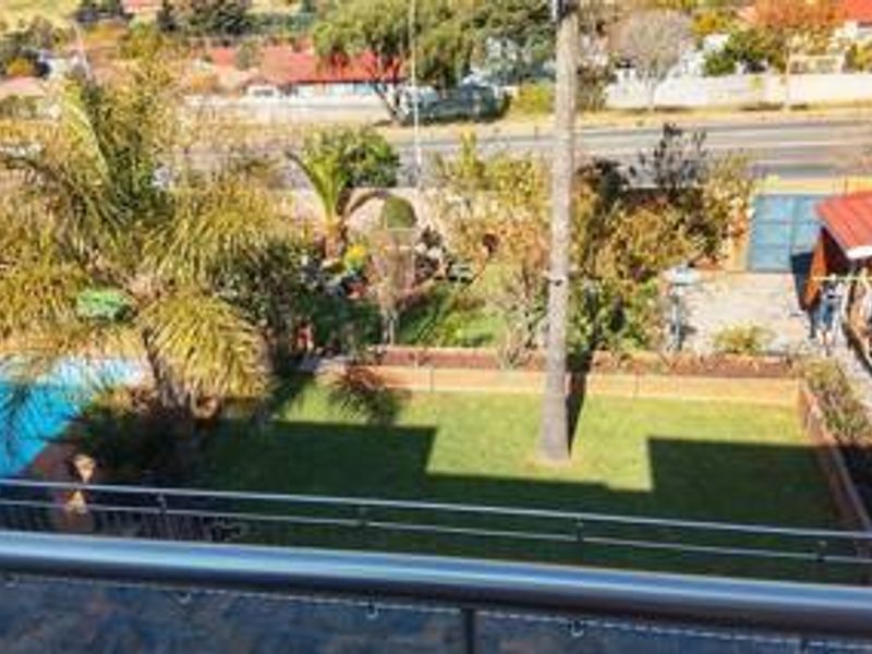 Elevated view overlooking a private garden with a swimming pool, lawn, and paved outdoor area.