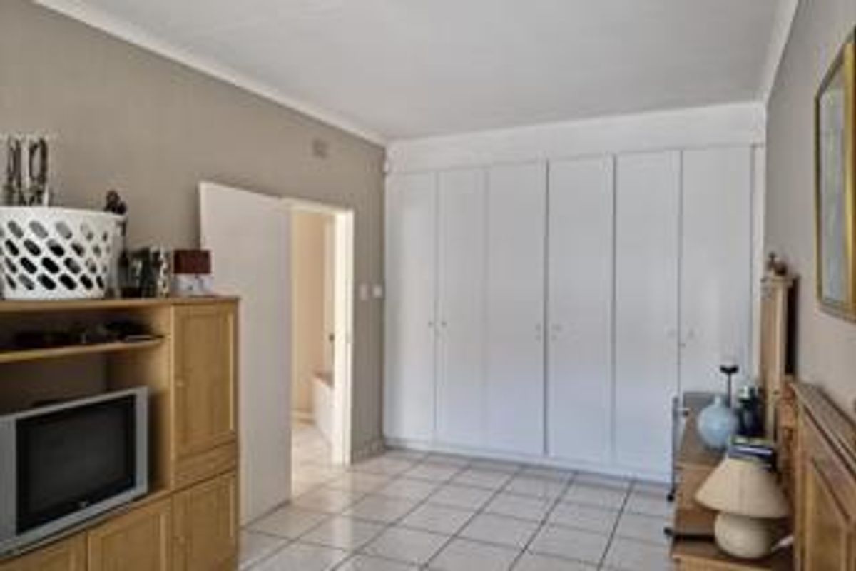 Bedroom featuring extensive floor-to-ceiling built-in cupboards, neutral wall finishes, and tiled flooring, offering ample storage space.