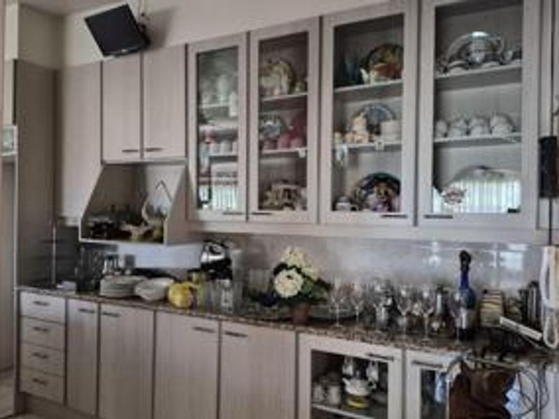 A functional kitchen featuring light-toned built-in cabinetry, granite countertops, and glass-front display units, providing ample storage and a classic aesthetic.