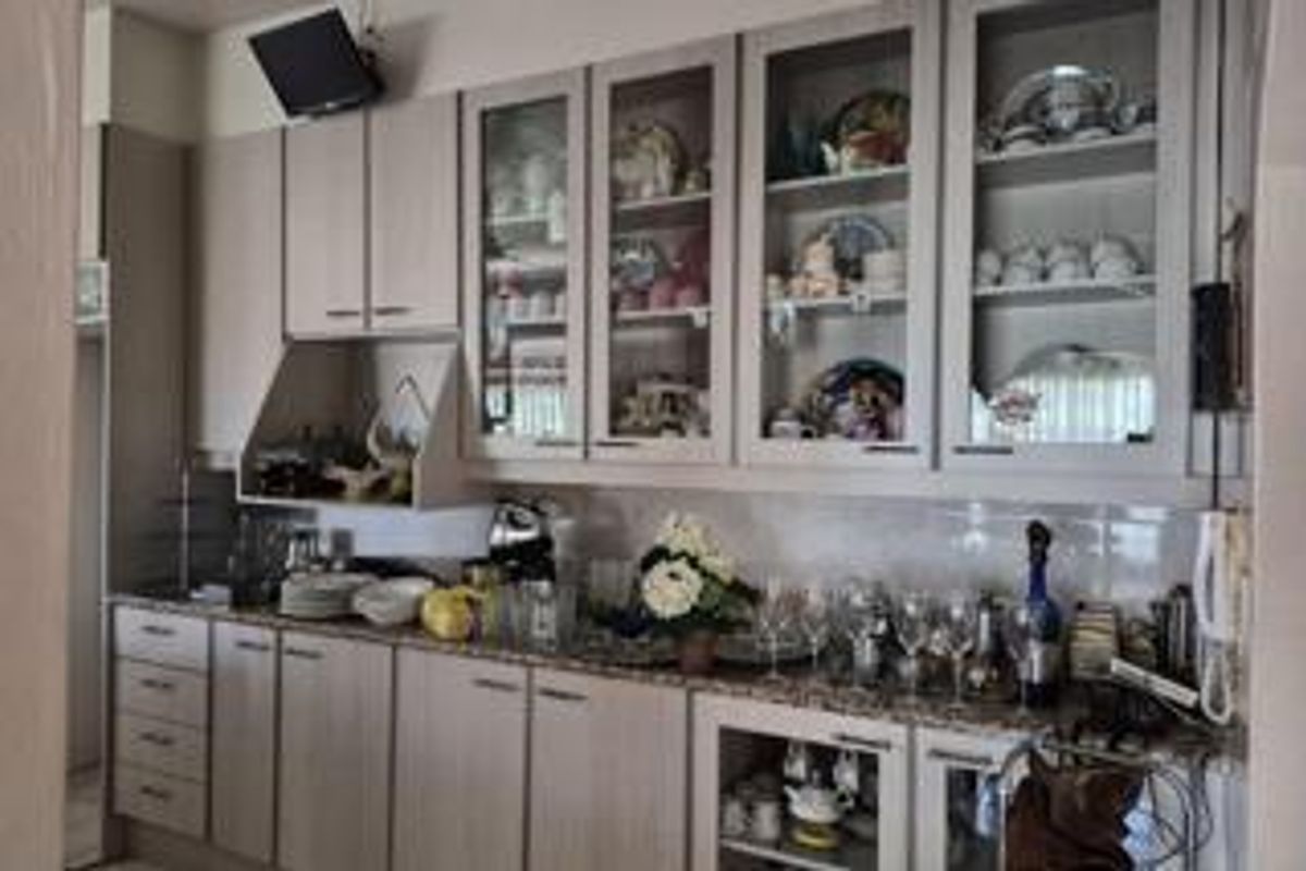 A functional kitchen featuring light-toned built-in cabinetry, granite countertops, and glass-front display units, providing ample storage and a classic aesthetic.