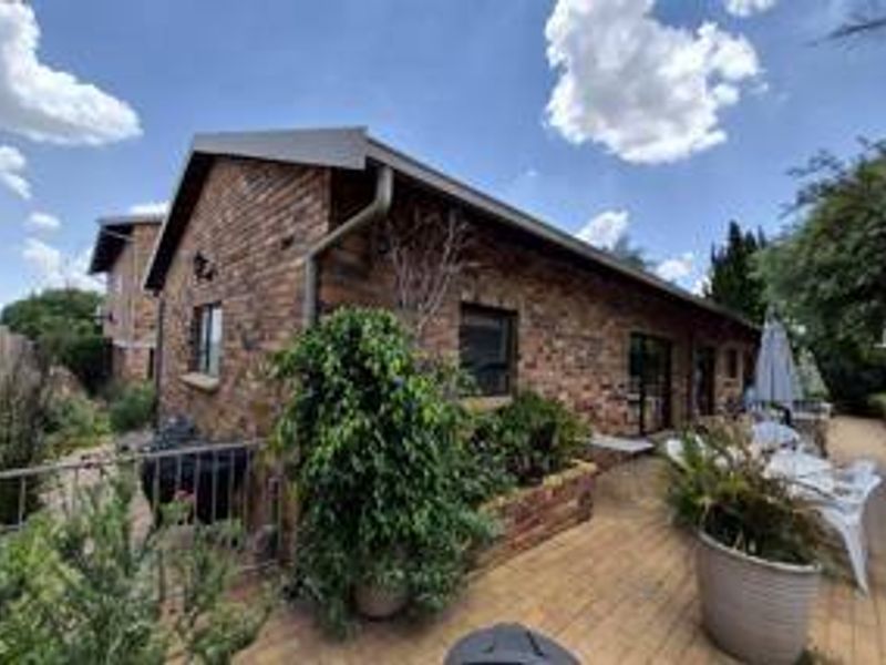 Rear view of the house featuring a face brick facade, paved patio area, and sliding glass door access.