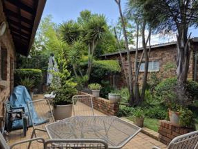 A paved outdoor patio area featuring brick retaining walls and established garden landscaping, providing a functional space for outdoor relaxation.