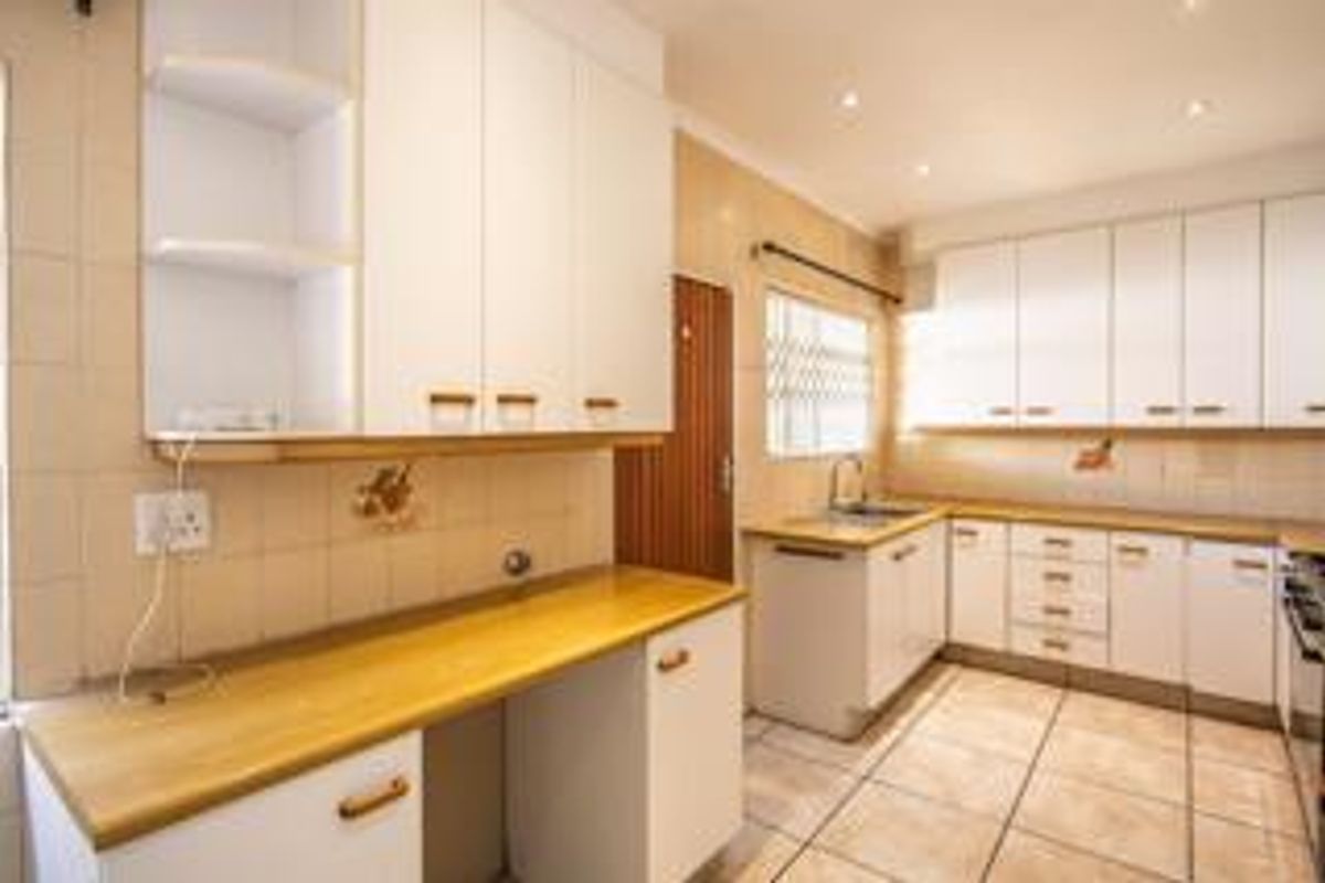 A functional kitchen featuring white built-in cabinetry, laminate countertops, tiled backsplash, and tiled flooring with ample storage space.