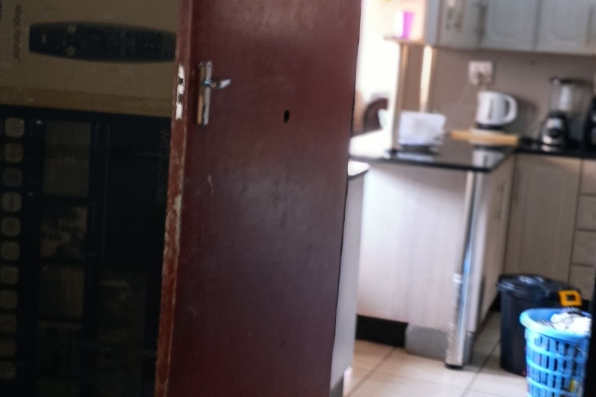 A view into a kitchen area featuring built-in cabinetry, stone countertops, and tiled flooring, partially obscured by a door in the foreground.