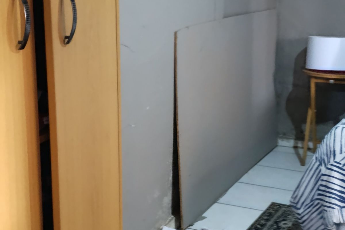 A bedroom interior showing a corner with tiled flooring and wall surfaces requiring maintenance.