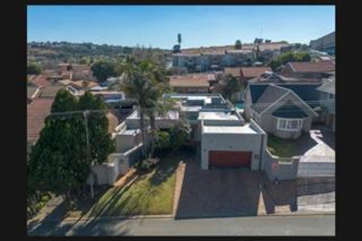 Aerial view of the property showing the front facade, paved driveway, garage, and surrounding residential neighborhood.