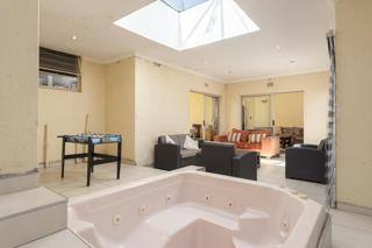 Spacious living area featuring a built-in spa bath, large skylight, and tiled flooring, offering a unique layout with direct access to adjacent rooms.