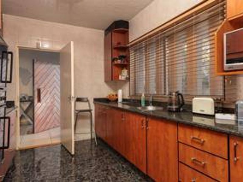 A functional kitchen featuring dark granite countertops, wood-finish cabinetry, and a built-in double wall oven with tiled flooring.