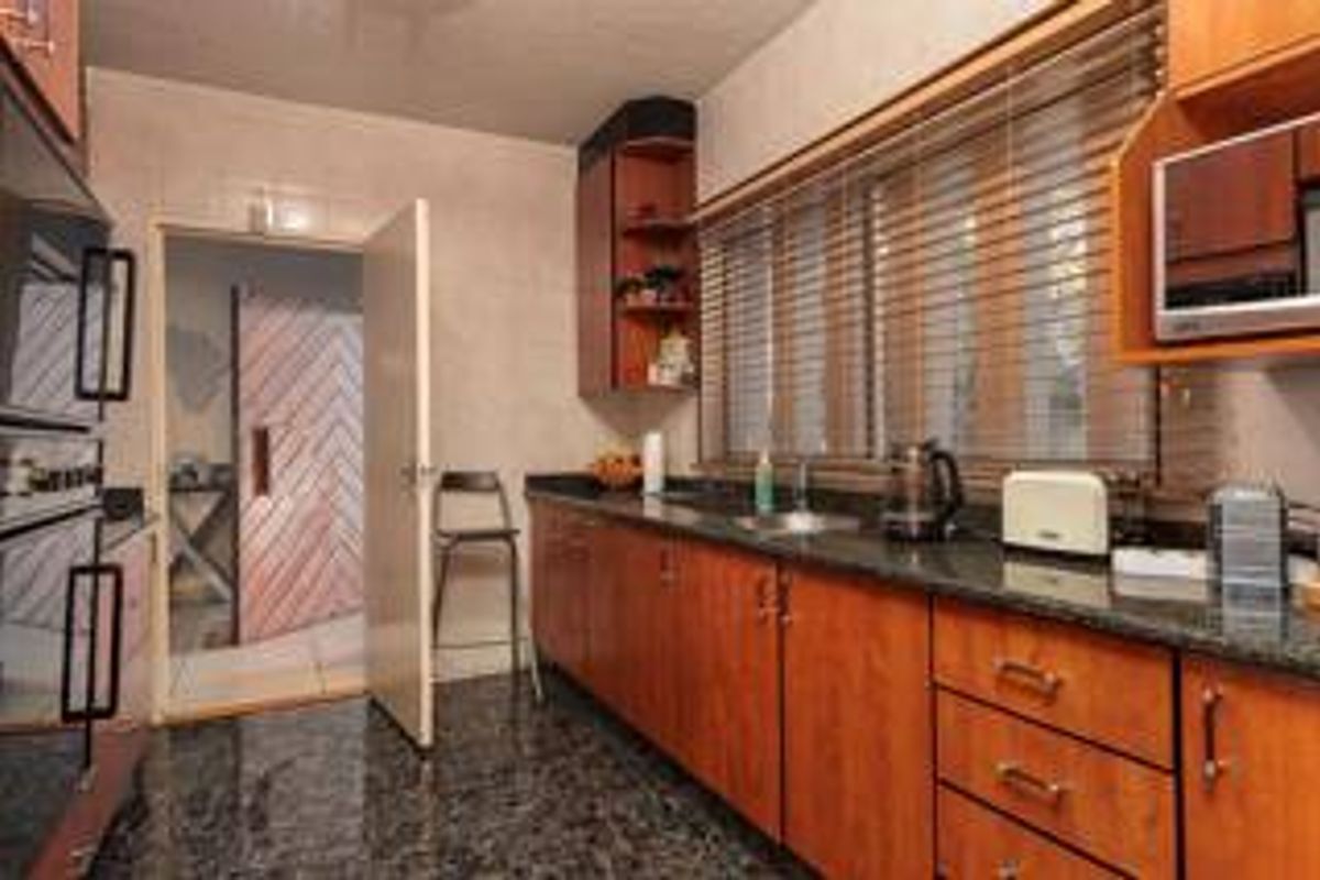 A functional kitchen featuring dark granite countertops, wood-finish cabinetry, and a built-in double wall oven with tiled flooring.