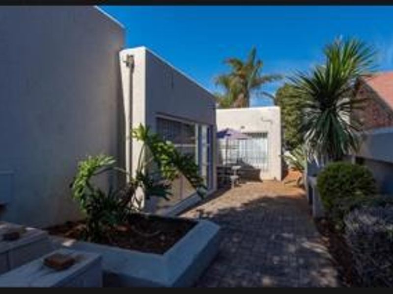 A paved rear courtyard area featuring a raised concrete planter and access to the home via sliding glass doors with security bars.