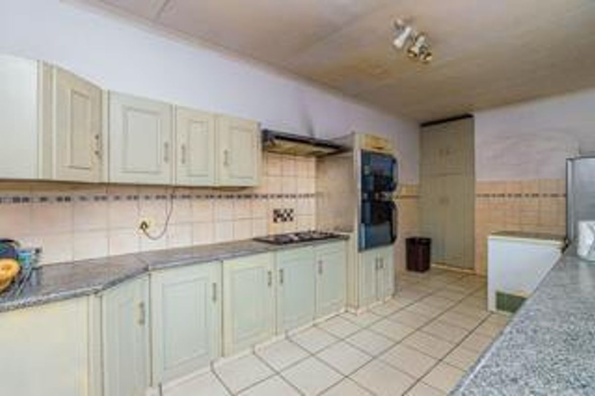 A dated kitchen featuring built-in cabinetry, tiled backsplash, and integrated oven and hob, offering significant potential for modernization and renovation.