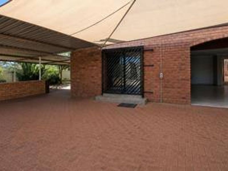 Covered outdoor patio area featuring brick paving, a shade sail, and a secure entrance leading into the home.