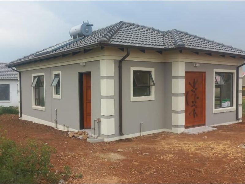 A modern single-story house exterior featuring a tiled roof, solar water heater, and neutral painted facade with contrasting corner detailing.