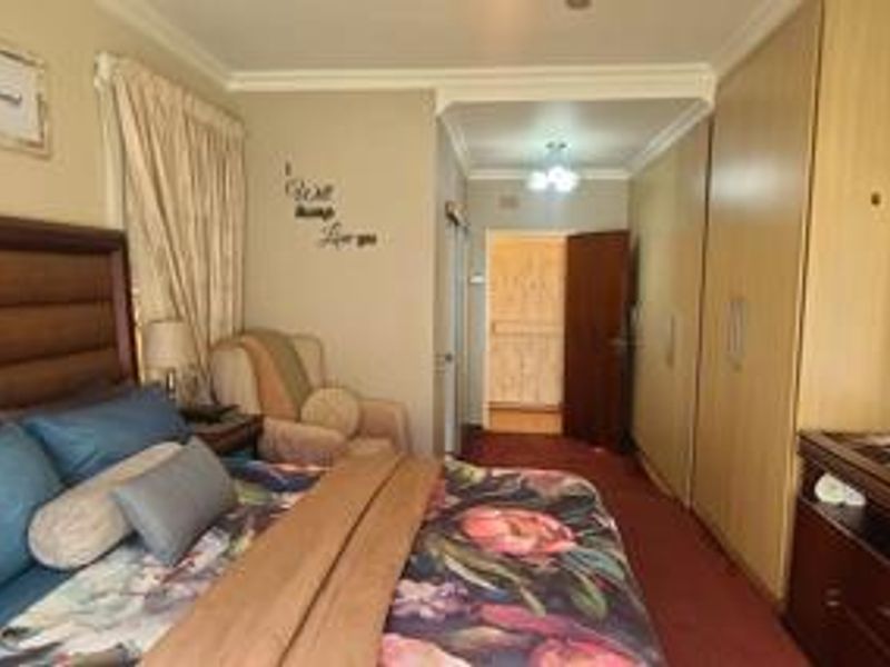 A bedroom featuring built-in cupboards, carpeted flooring, and decorative coving, providing a functional and comfortable sleeping space.