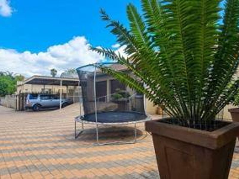 A paved front driveway area featuring a functional carport and perimeter boundary walling.