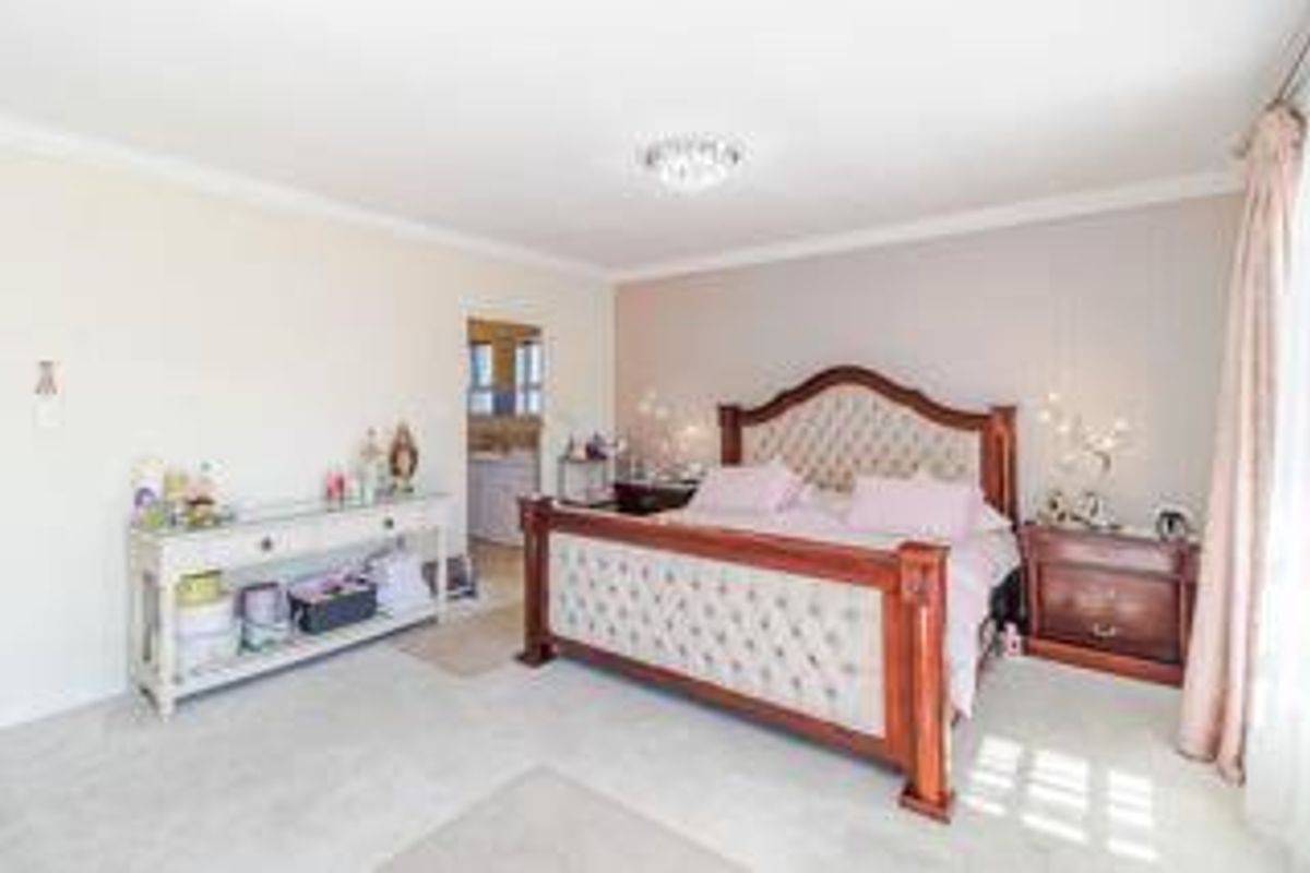 Spacious primary bedroom featuring neutral wall finishes, carpeted flooring, decorative coving, and direct access to an en-suite bathroom.