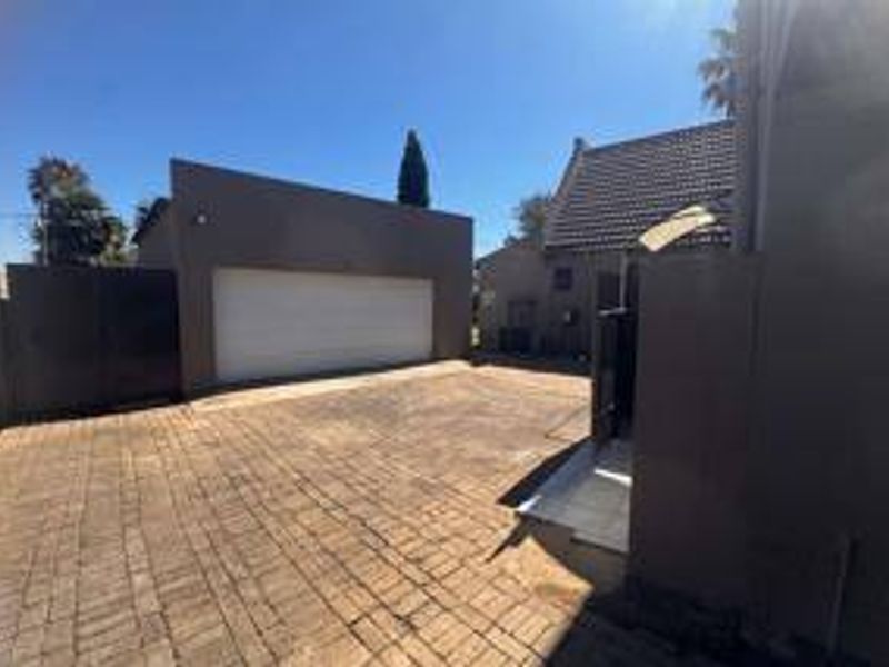 A paved driveway leading to a double garage with a tiled roof and secure boundary walls.